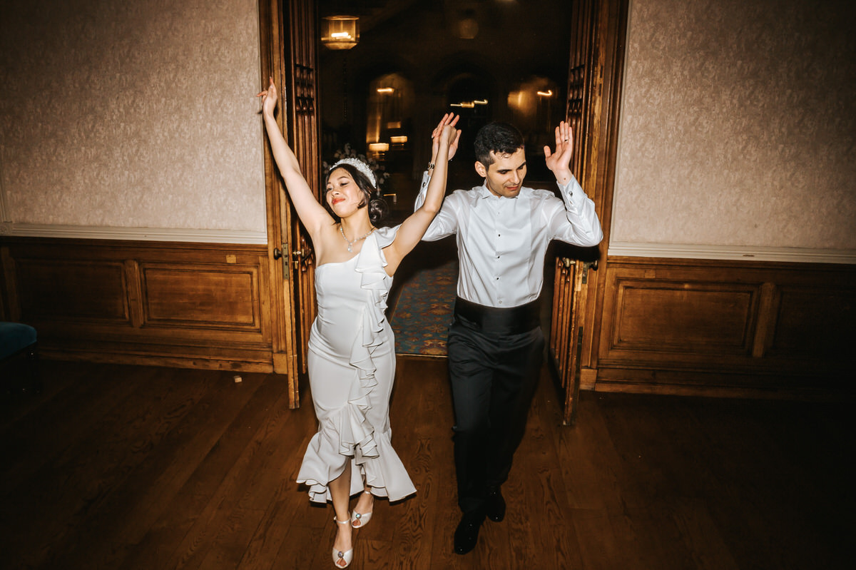 ashridge house wedding newlyweds entering the gret hall celebrating with arms up