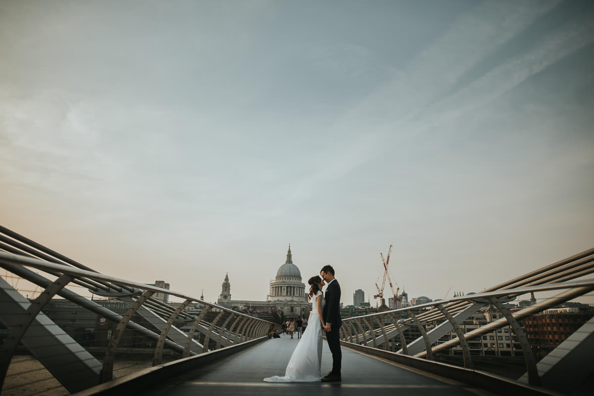 wedding couple posing on millenium bridge in london