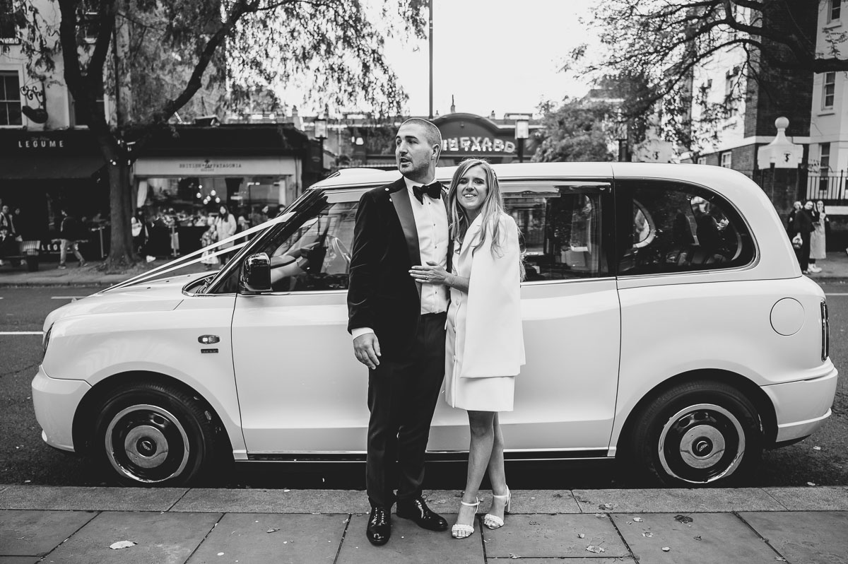 islington town hall wedding newlyweds standing ouside by a taxi