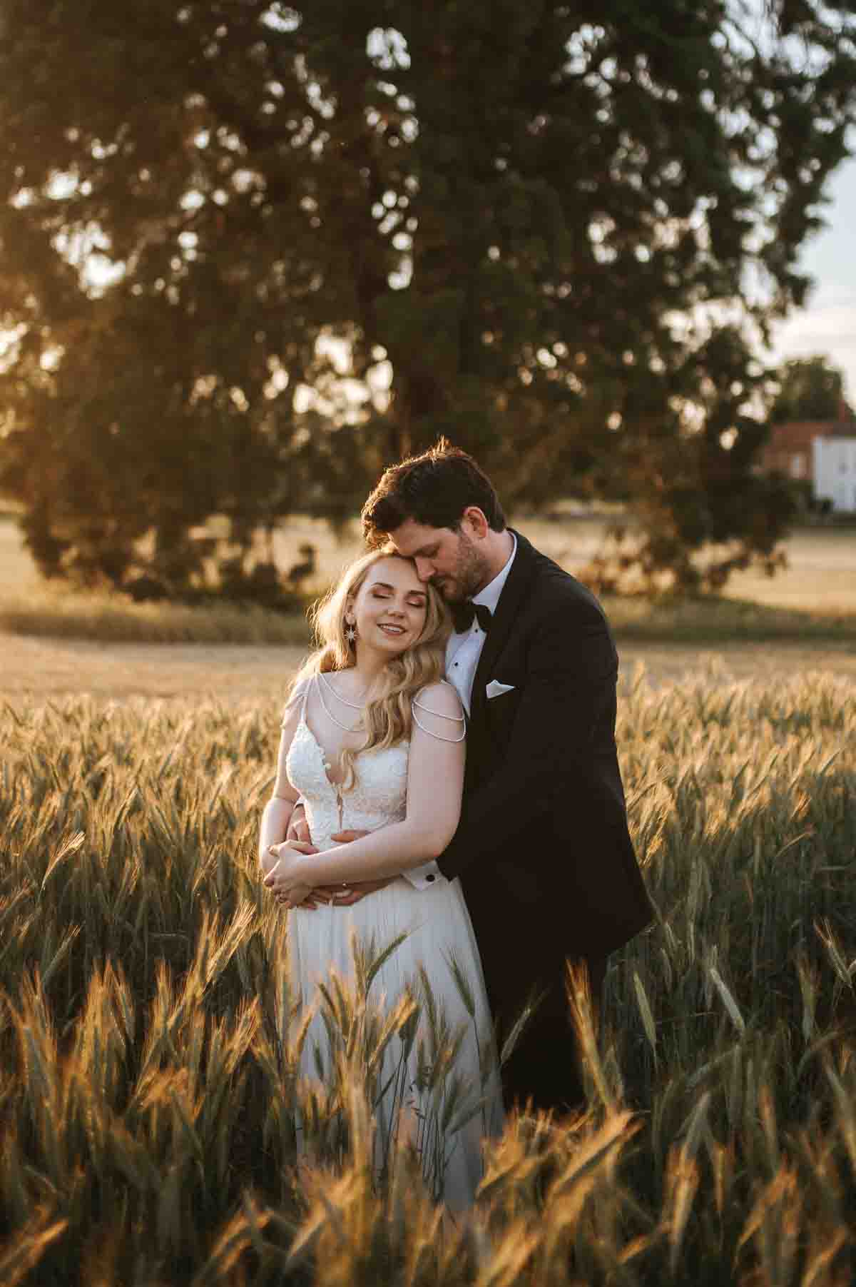 gosfield hall wedding couple posing in the field with golden light