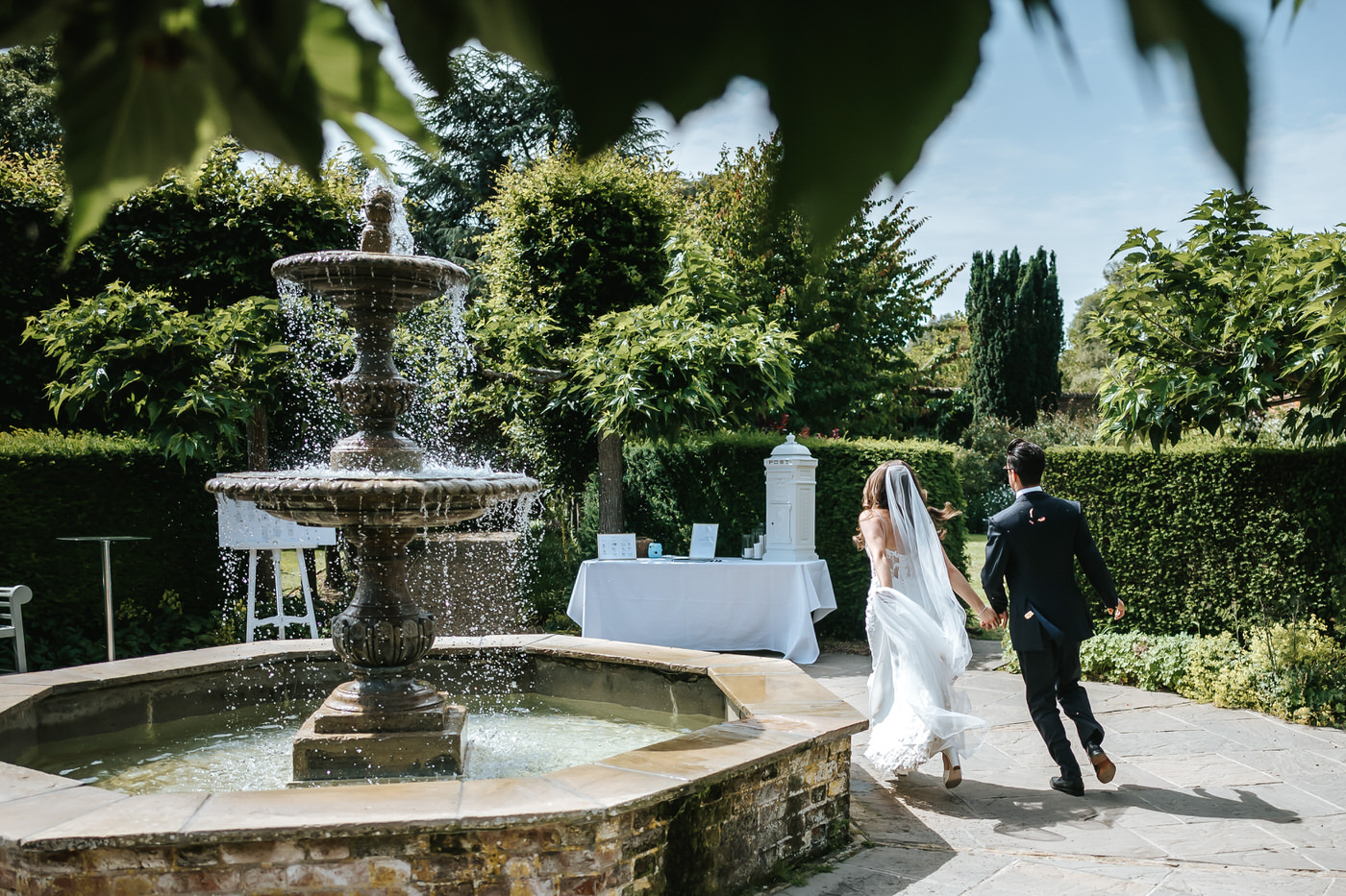 braxted park wedding couple running by the fountain