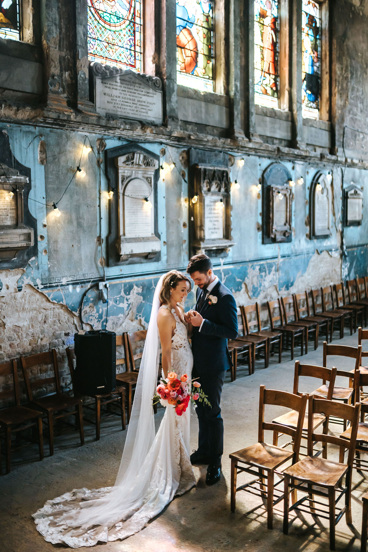 asylum chapel wedding bride and groom standing close inside the chapel with colourful stained glass windowns in the background