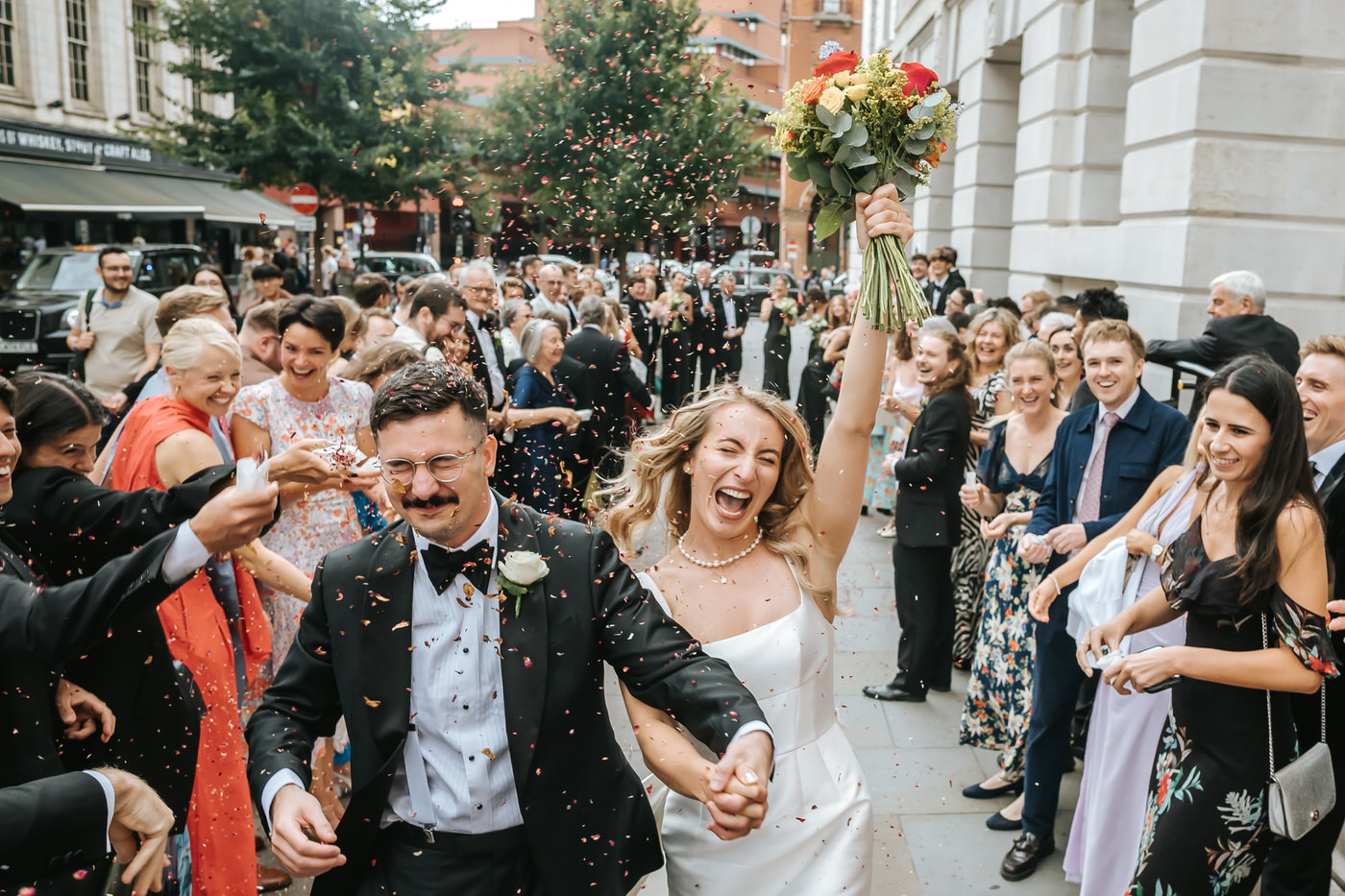 Camden Town Hall wedding explosive confetti shot with bride lifting the flowers and groom dodging the confetti