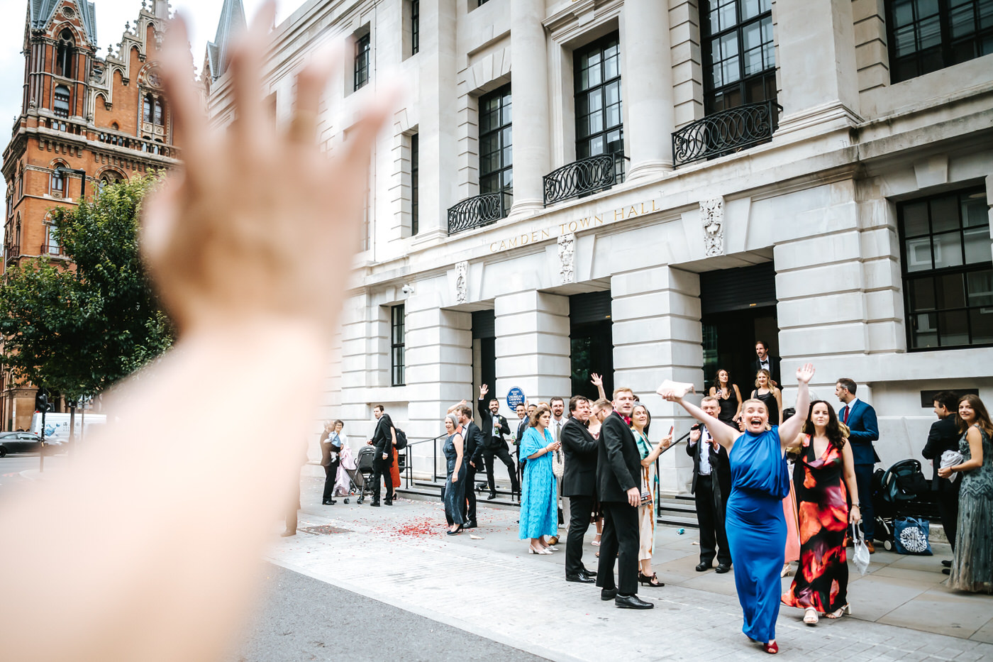 Camden Town Hall wedding couple shoot waving to wedding guests from the taxi