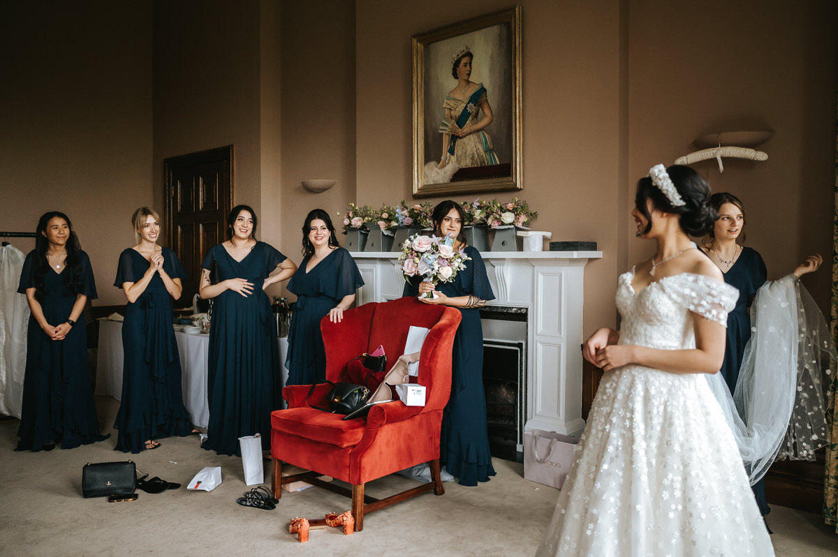 ashridge house wedding getting ready first look with bridesmaids looking at bride in her dress