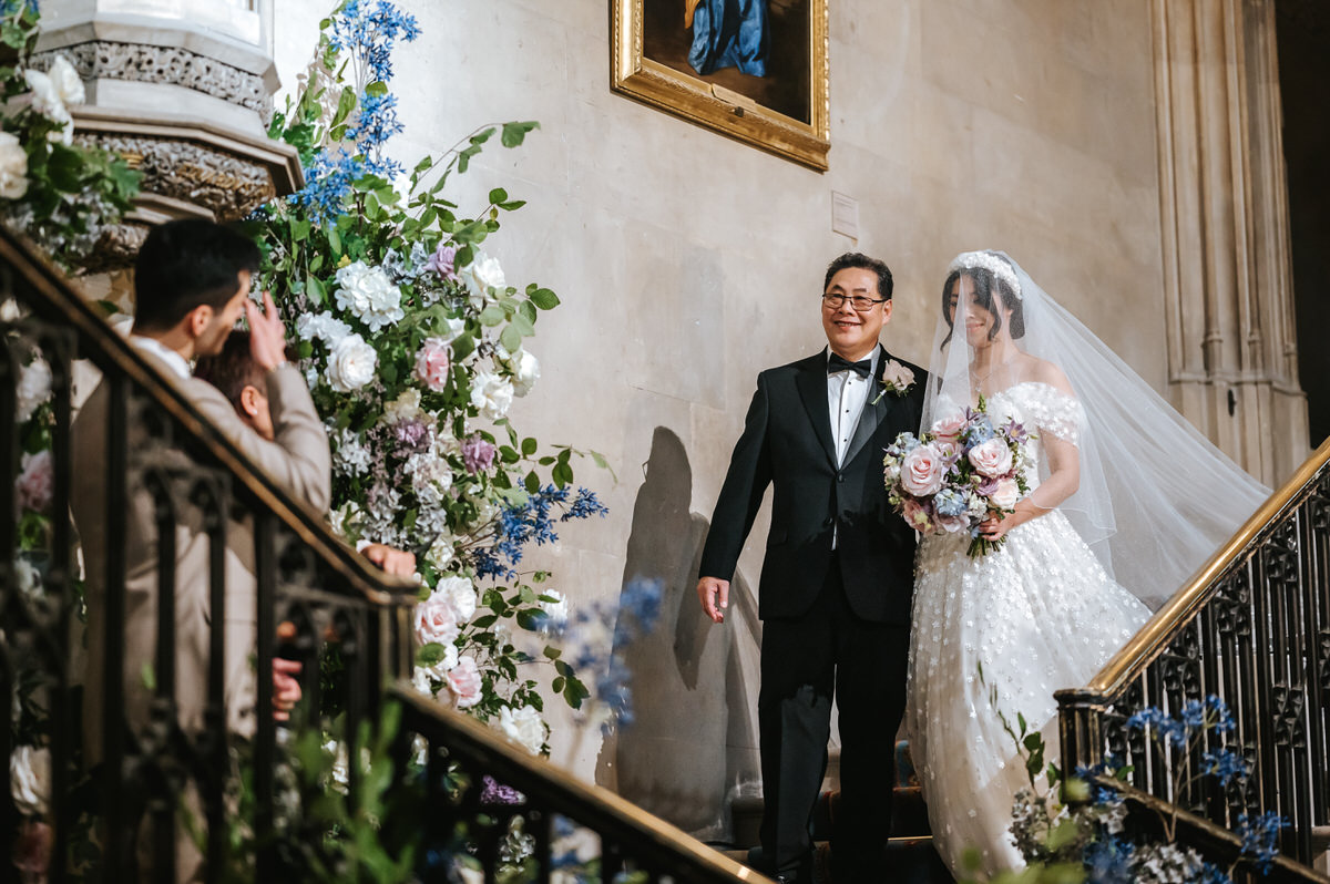 ashridge house wedding ceremony bride going down the stairs with her father and groom looking at her crying