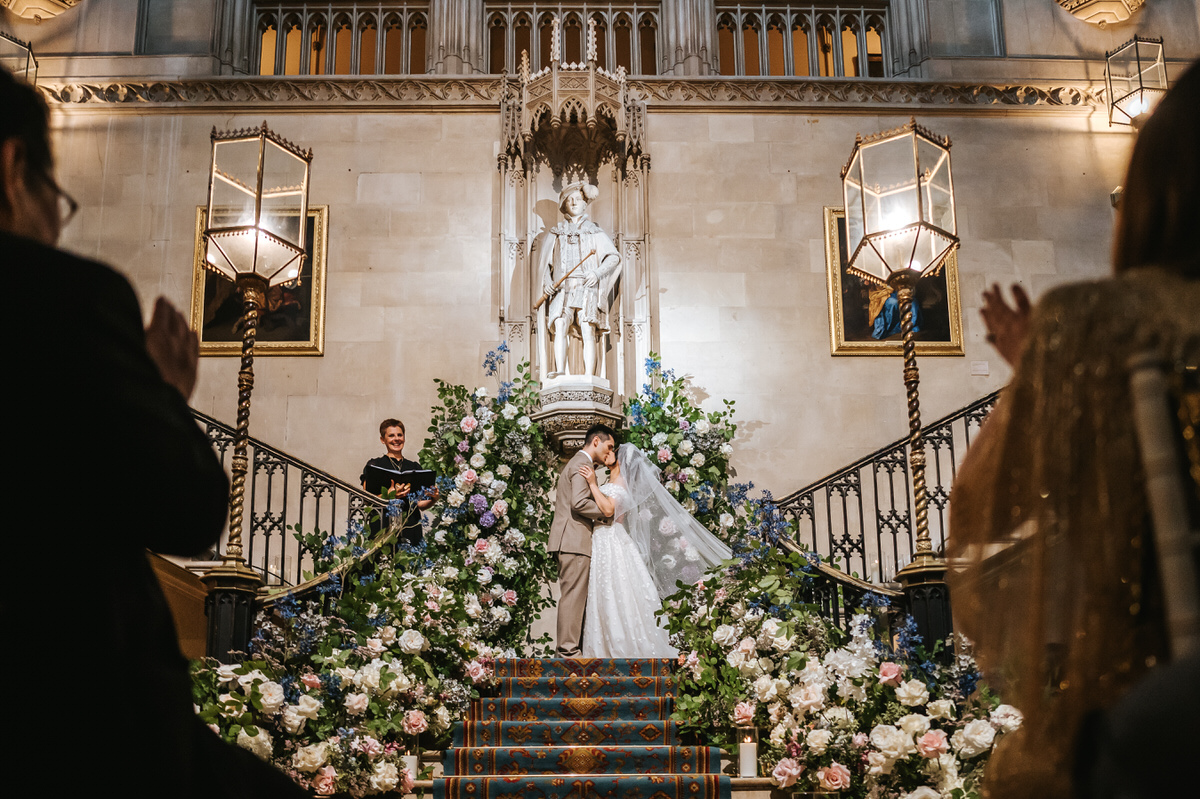 ashridge house wedding ceremony first kiss on the grand staircase with guests clapping on the sides