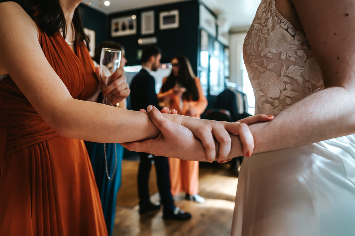 london rowing club wedding close up on the hands of the bride and her best friend holding hands