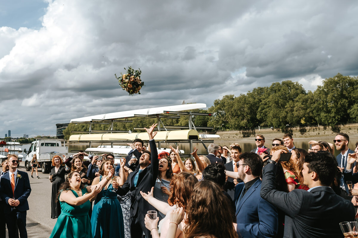 london rowing club wedding flower toss with rowing boats in the background