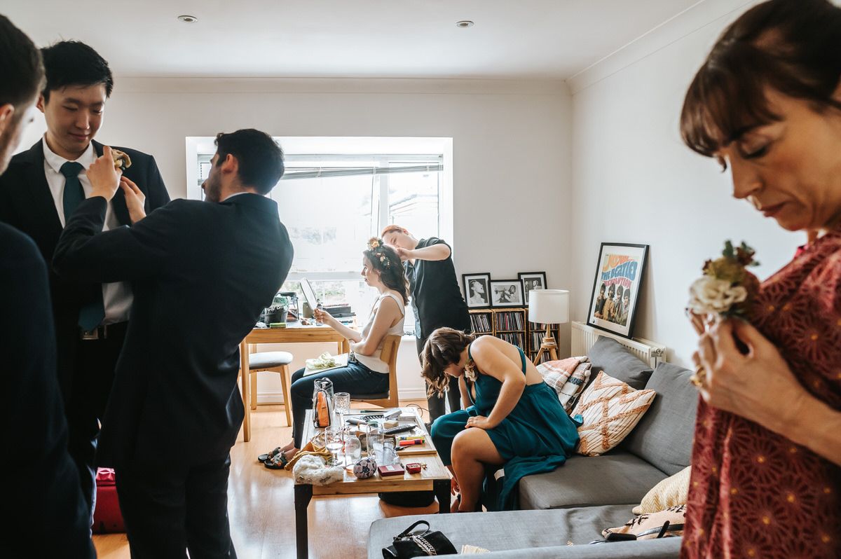 london rowing club wedding getting ready with the bride having her hair done and guests doing up their buttonholes