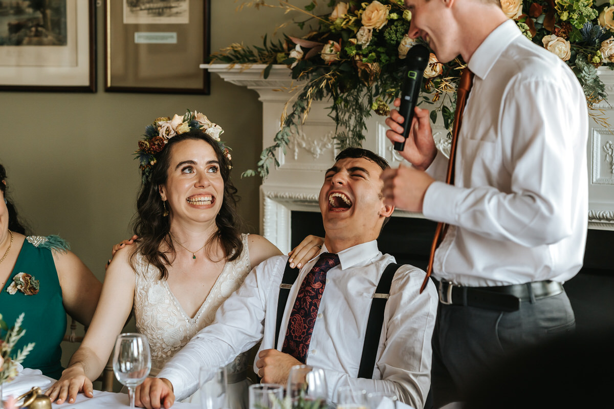 london rowing club wedding close up on newlyweds laughing during best man speech
