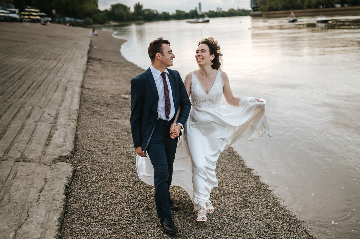 london rowing club wedding couple strolling along river thames holding hands
